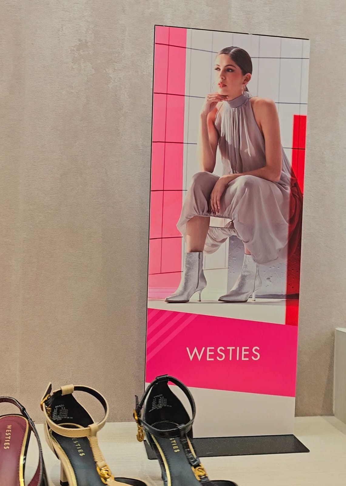 Display vertical de campaña junto a una exhibición de calzado en punto de venta