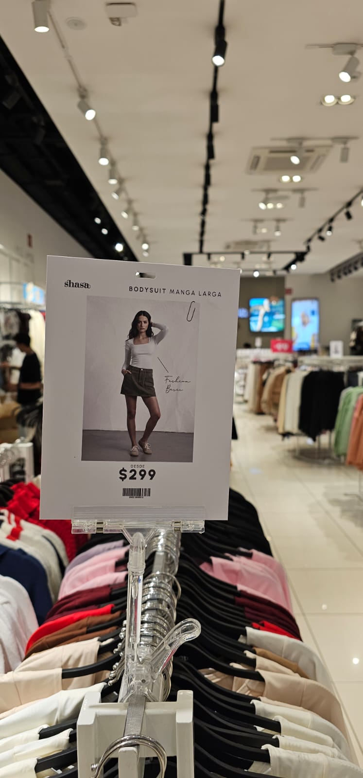 Señalización de producto y precio colgada sobre un exhibidor de ropa en tienda